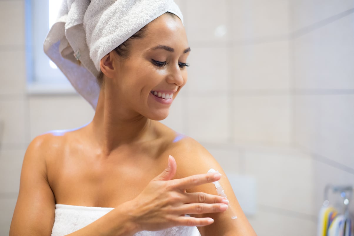 Woman moisturizing skin in the bathroom